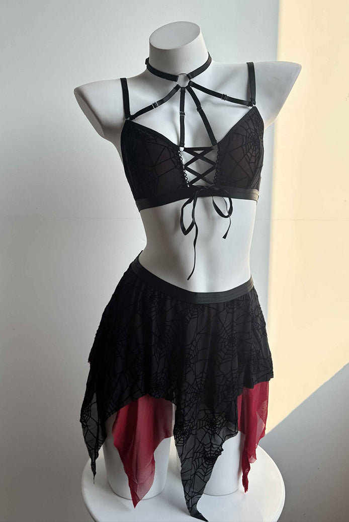 Black spider-web lace bra and asymmetric mini skirt set on mannequin with neck tie detail and red panel