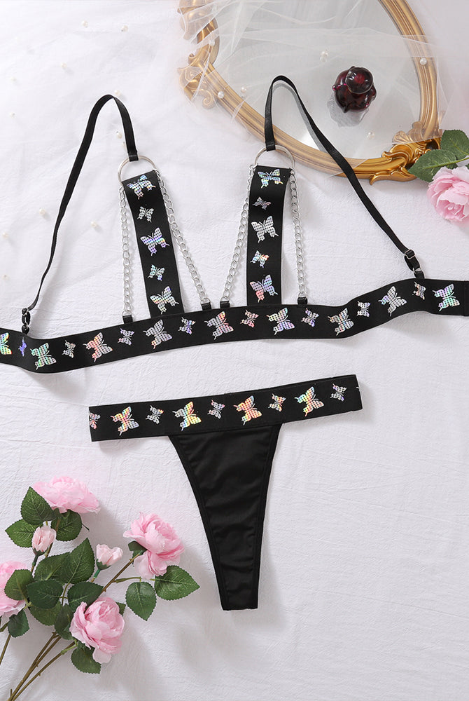 Black butterfly print lingerie set: chain-strap bra top and matching thong, flat lay