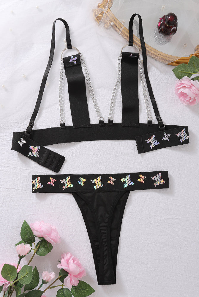 Black butterfly print lingerie set with chain-strap bra and thong, flat lay