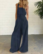 Navy blue wide-leg bib romper with adjustable straps and side button placket