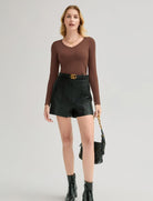 Brown long-sleeve V-neck top styled with a dark leather mini skirt