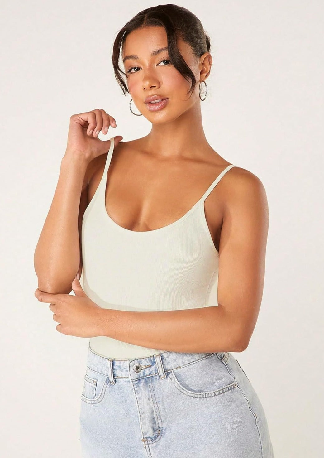 Beige ribbed tummy control romper with thin straps and scoop neck, hand at shoulder strap