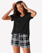 Black V-neck T-shirt and black-and-white plaid pajama shorts, side view