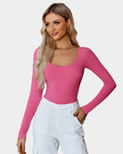 Scoop neck bodysuit shapewear in pink, long sleeves, fitted thong bottom.