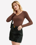 Brown long-sleeve V-neck top styled with a dark mini skirt
