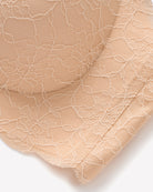 Nude lace bra fabric close-up with floral texture and mesh-like overlay