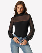 Black mesh long-sleeve turtleneck bodysuit tucked into blue jeans