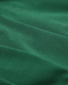 Green pleated mini skirt fabric close-up with vertical pleat texture