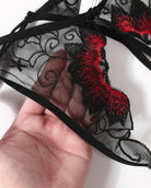 Black mesh thong panty with floral embroidery and scalloped lace trim in red.