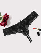 Black lace thong panties with bow and ribbon ties, angled flat lay