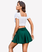 Green pleated mini skirt with ruched drawstring waist, side tie cords, flared hem.