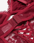 Wine red lace V-neck mini bodysuit close-up of crisscross lacing and adjustable strap tape