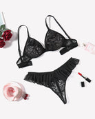 Black mesh lace bra and thong panty set with ruffle trim, laid out