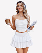 White pleated mini skirt with layered ruffle hem and drawstring bow detail at waist