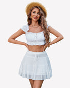 White pleated mini skirt with tiered ruffle layers and elastic waistband