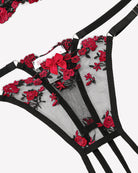 Sheer lace underwire bra with black straps and red floral embroidery, close-up