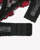 Black bra back band with adjustable hooks, red floral lace trim, close-up