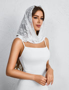 White lace mantilla veil with floral embroidery and scalloped edge, draped over head.