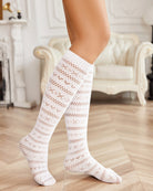 White knee-high mesh socks with hollow-knit pattern and ribbed top cuff, close-up view