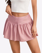Pink solid ruffle mini skirt with elastic gathered waistband and flared tiered hem