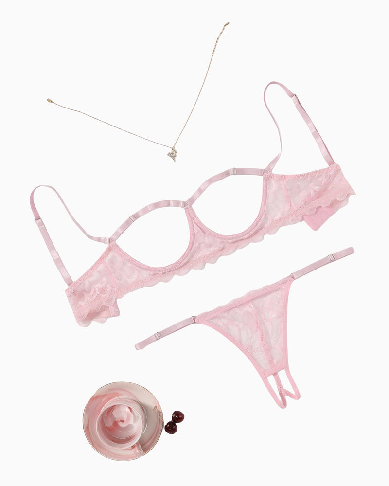 Lace bra and thong-style panty set with scalloped lace trim, pale pink, flat lay.