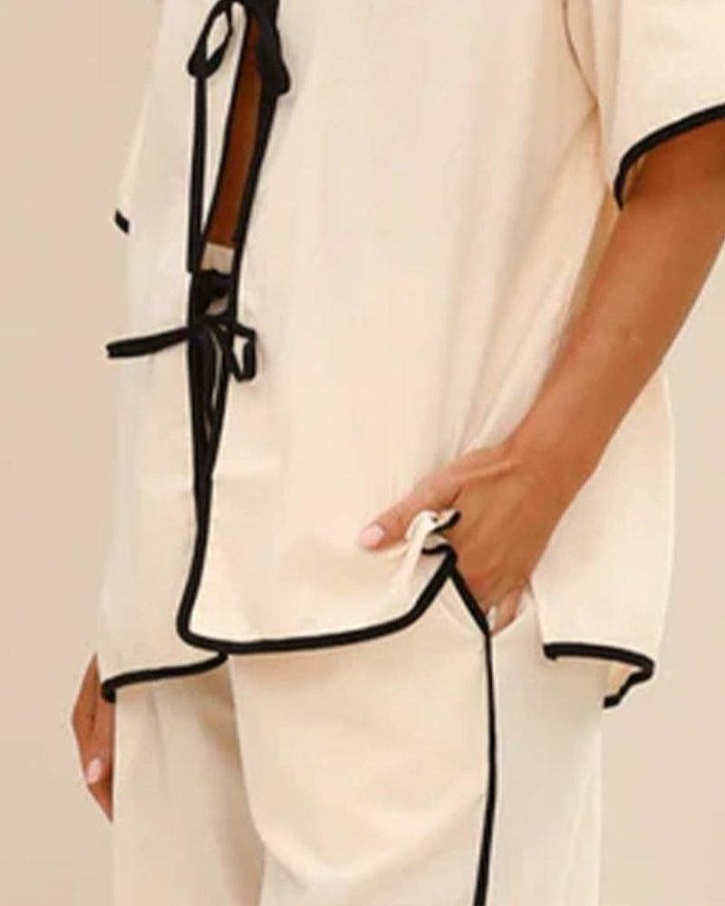 Beige linen pajama shirt front with lace-up ties and black trim detail.