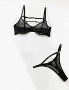 Black sheer mesh bra and panty set with ladder straps and ring detail, flat lay