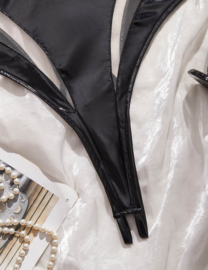 Close-up of black PU leather bodysuit open crotch seam and mesh side panel.