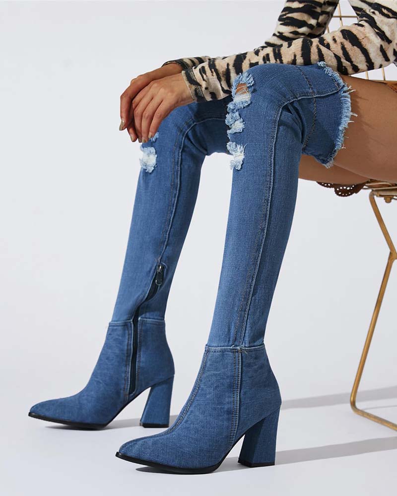 Distressed over-the-knee stiletto boots in blue denim, pointed toe, tall block heel, side zip.