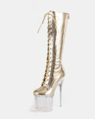 Gold metallic knee-high stiletto boot with lace-up front and clear platform heel