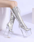 Silver metallic knee-high lace-up stiletto boots with clear platform heel, standing view
