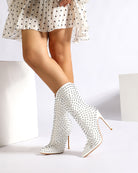 White mid-calf stiletto boots with pointed toe and silver spike studs on heel