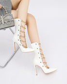 White patent stiletto ankle boots with gold chain wrap and pointed toe.