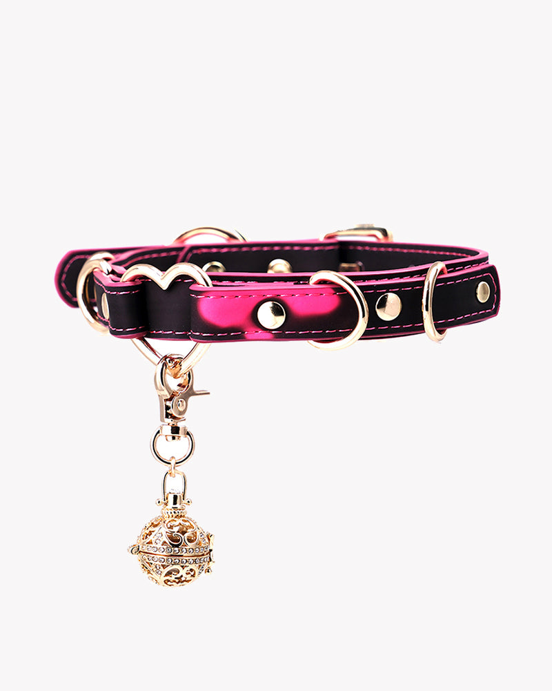 Heart-shaped leather dog collar with pink interior, metal rings, and bell charm