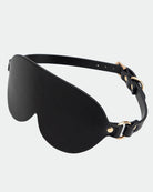 Black leather eye mask with curved eye cup shape and adjustable strap with metal rings