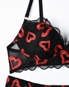Close-up of black lace bra with red lip embroidery and scalloped lace trim
