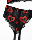 Close-up of black lace lingerie panty with red heart embroidery and scalloped lace trim