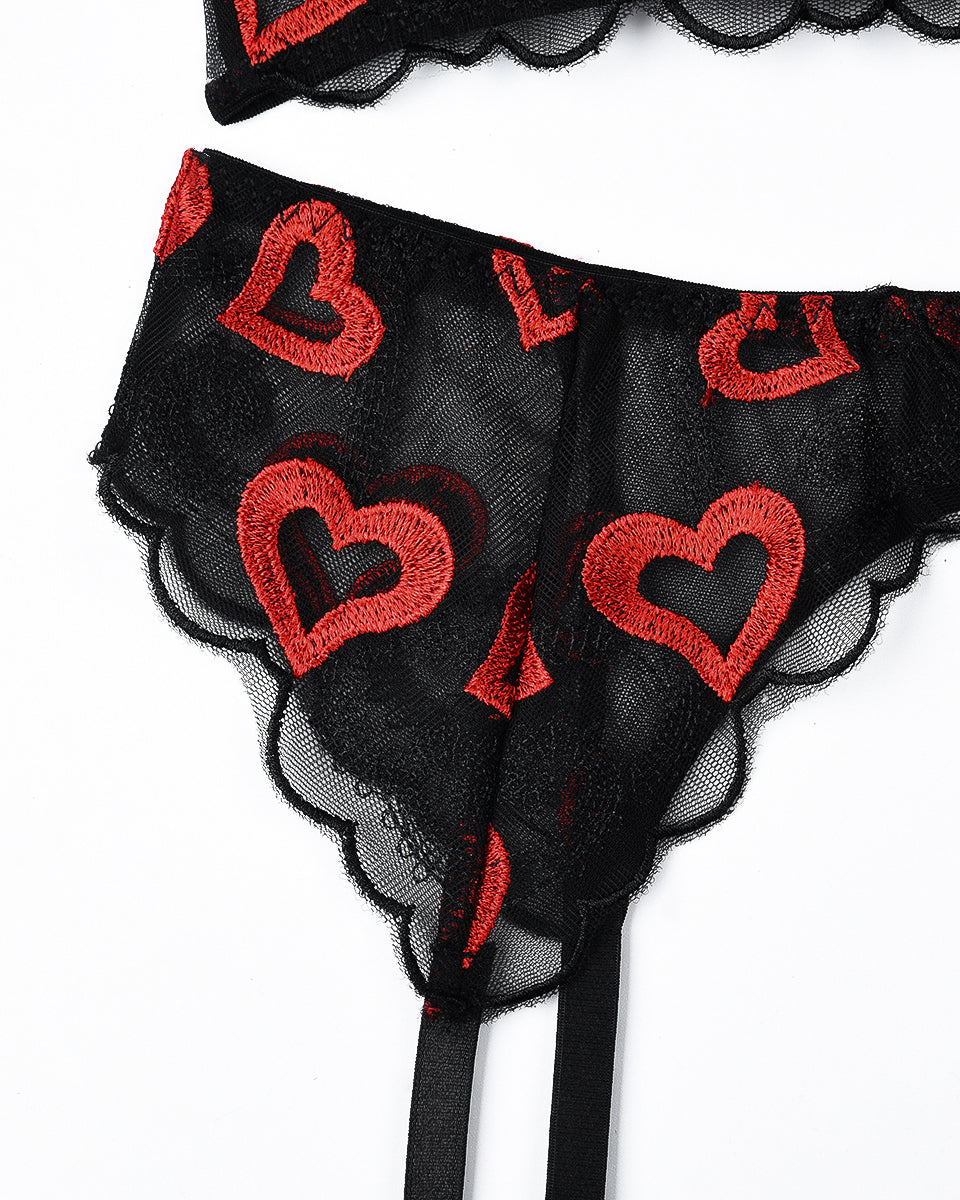 Close-up of black lace lingerie panty with red heart embroidery and scalloped lace trim