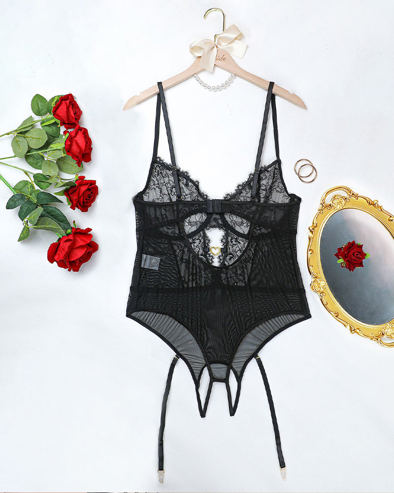 Black floral lace bodysuit set flat on hanger with lace bodice, garters, and thong