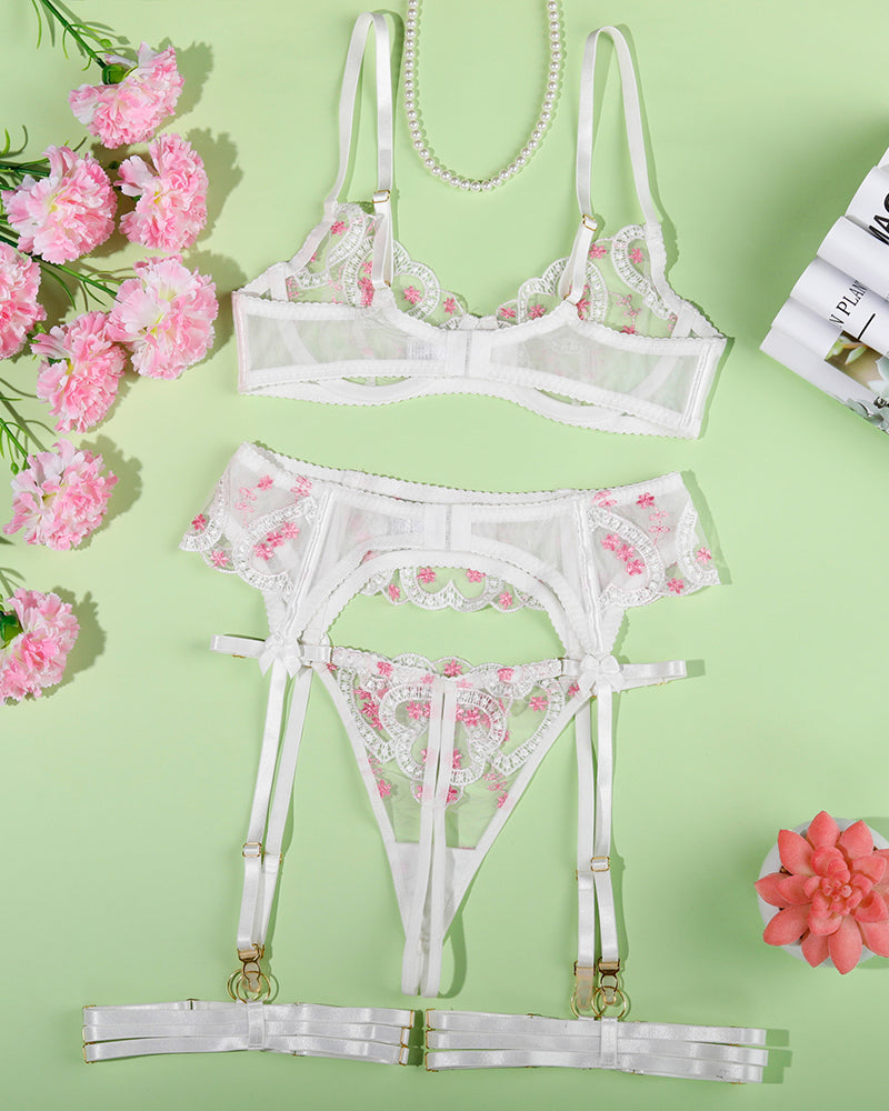 Flat lay of white lace heart-embroidered bra and garter thong with adjustable thigh straps.