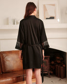Black satin robe with lace-trim cuffs and tie belt, worn over slip dress