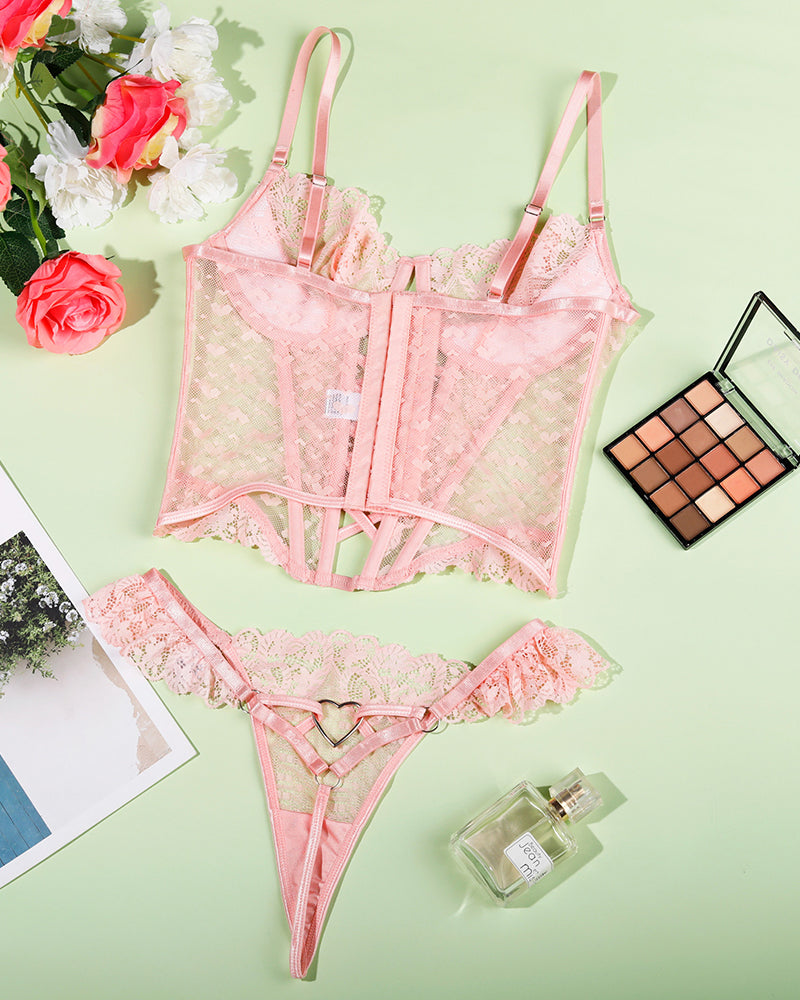 Pink lace lingerie corset set with heart detail, bra and thong laid flat