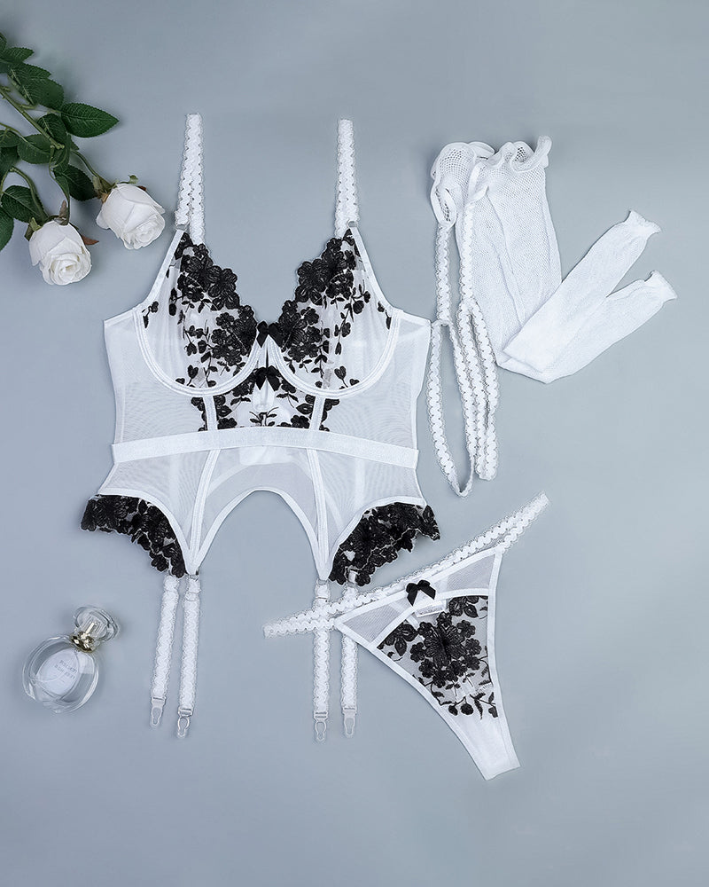 White embroidered corset set flat lay with garters, thong, fishnet stockings, and gloves
