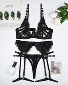 Black lace lingerie set laid flat: bra, garter belt, and thong with straps