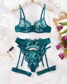 Teal embroidery lace lingerie set laid flat: bra, briefs, and garter belt with straps