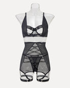 Black mesh lingerie set on mannequin with harness-style straps and garter belt