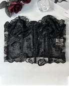 Black strapless mesh corset top flat lay with floral embroidery and boning seams