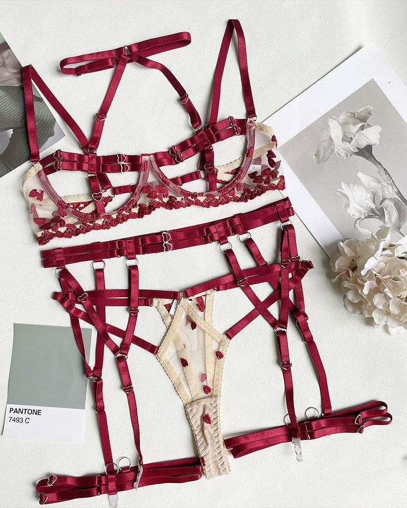 Red strappy lingerie pieces arranged flat: bra, garters, and heart-ring thong