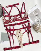 Red strappy lingerie pieces arranged flat: bra, garters, and heart-ring thong