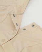 Beige front clasp bra detail: button placket and metal snap-style closures
